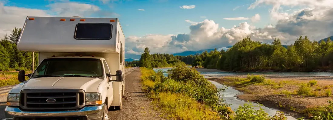 Camper parked beside river in the evening sun. Find South Carolina RV Insurance.