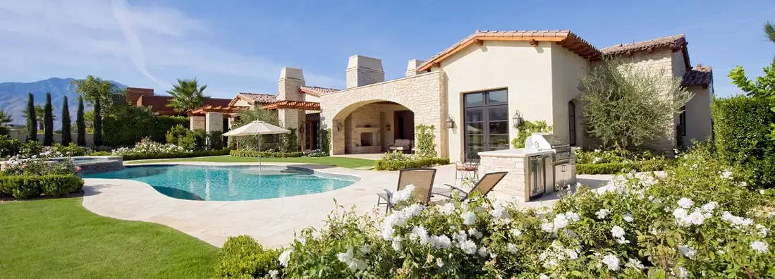 House exterior with a garden, plants, a swimming pool and hills in the far distance. Find Irvine, California home insurance.