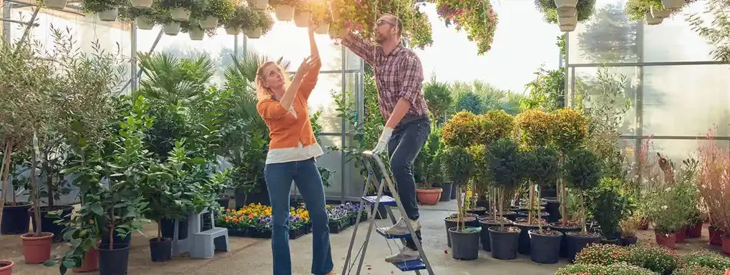 Man and woman working in a flower greenhouse taking care of plants. Workers' Comp for Retail Businesses.