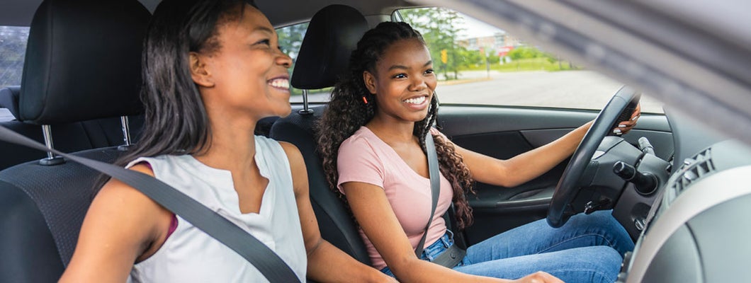 Teenage driver seated in her new car with her mother. Find Fayetteville, North Carolina car insurance.