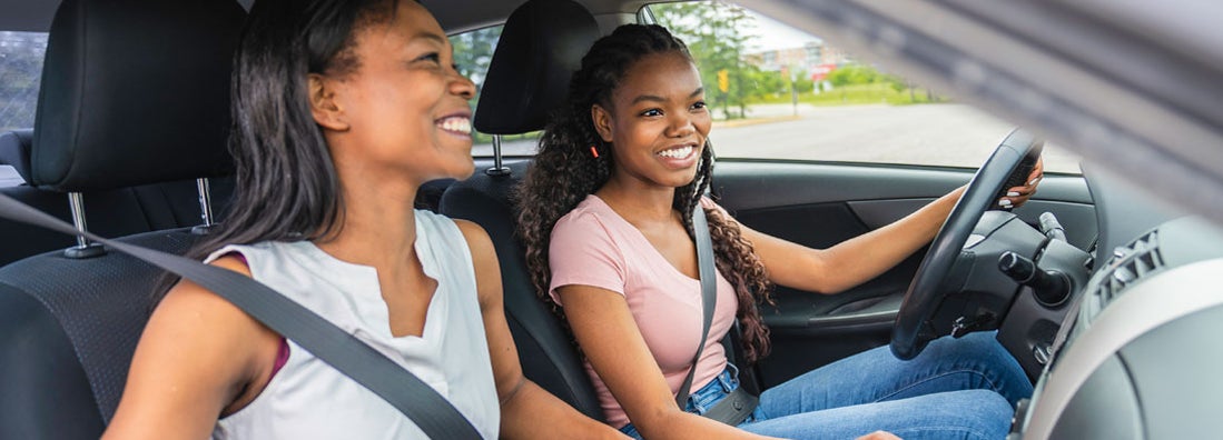 Teenage driver seated in her new car with her mother. Find Fayetteville, North Carolina car insurance.