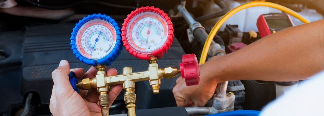 Auto mechanic using gauge air conditioning pressure in auto vehicle. Find auto air conditioning repair shop insurance.