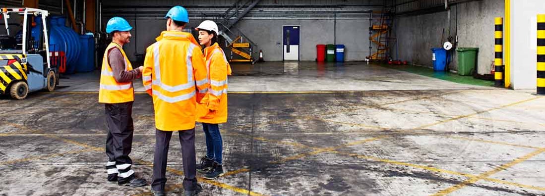 Three workers talking together while standing on a commercial dock. Essential Guide to Your Workers' Compensation Policy.