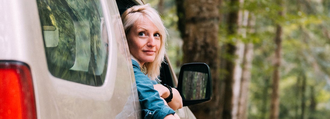 Rear view of a woman in a car leaning at window and smiling. Find Birmingham Michigan car insurance.