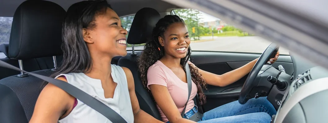 Young driver seated in her new car with her mother. Best Car Insurance for Young Adults.
