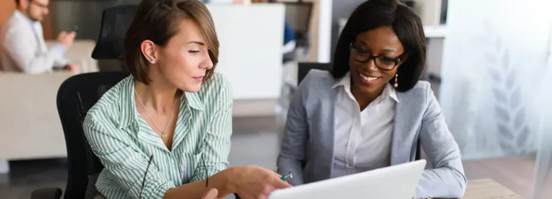 Businesswomen looking at laptop in office. Find Bellaire, Texas business insurance.