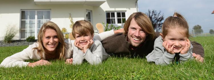 A family lays in the grass outside their new home.