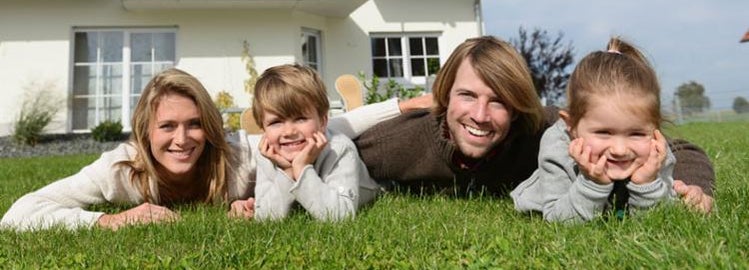 A family lays in the grass outside their new home.