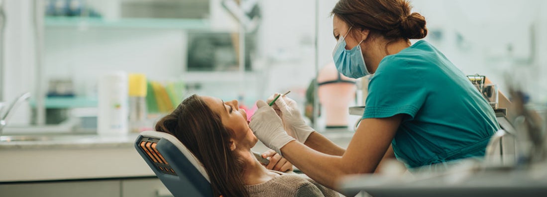 Young woman having her teeth checked during appointment at dentist's office. Find Dental Malpractice Insurance.