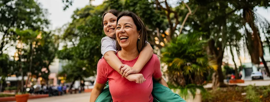 Mother and daughter doing piggyback outdoors. Get Life Insurance Quotes.