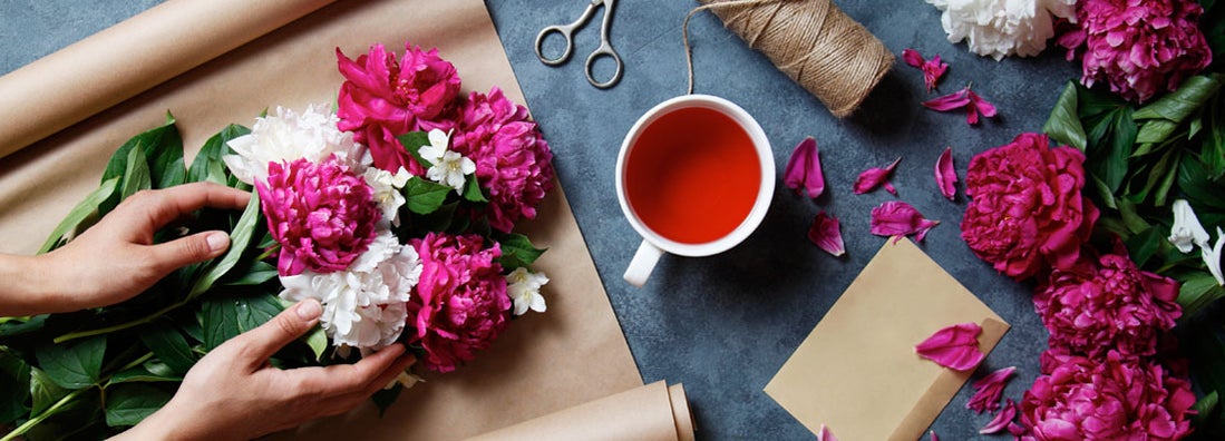 Florist at work: making summer bouquet of peonies on a working gray desk. Find Florists Insurance.
