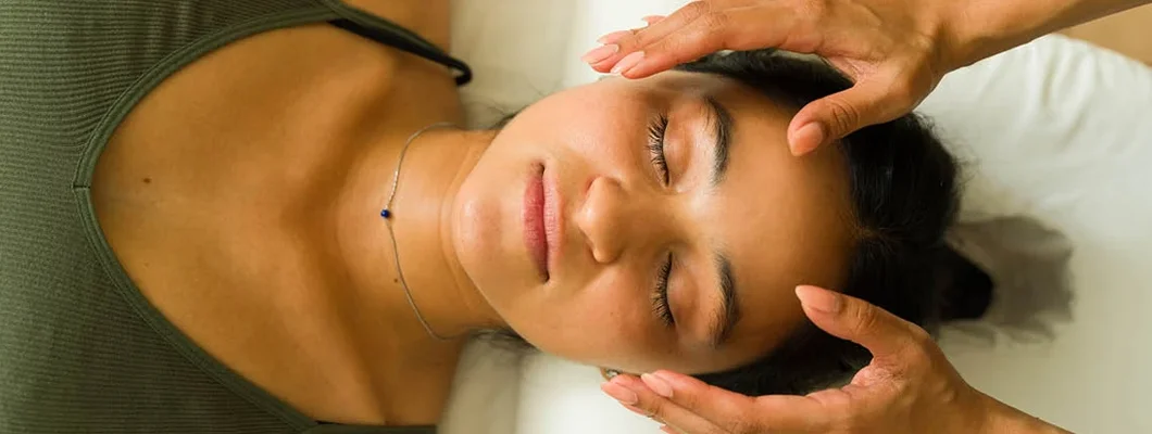 Woman lying on the massage table getting a reiki energy treatment at an alternative wellness center. Find Reiki Insurance.