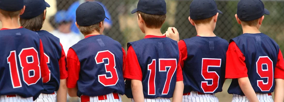 Little League players standing in line before a game. Sports Team Insurance for Youth Leagues: Find Coverage Today.