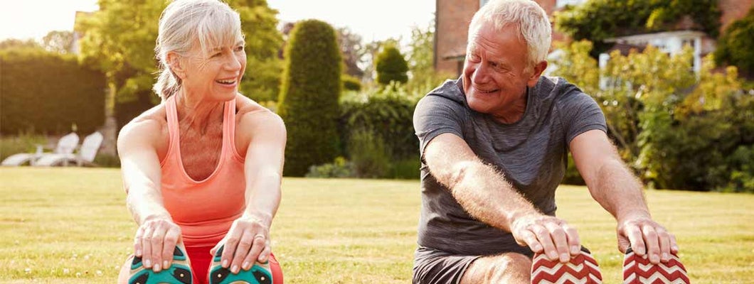 Fit mature couple stretching on the grass. Find Permanent Life Insurance.