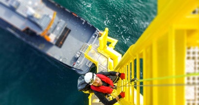 Manual high worker offshore climbing on wind-turbine on ladder. Find workers compensation FAQs.