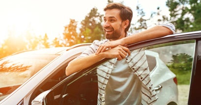 Man stands near the car on the background of the forest. 8 of the Best Used Cars Under $15,000. 