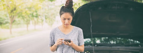 Woman using mobile phone after a car breakdown on street