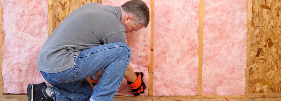 Man installing fiberglass insulation in the wall. Find fiberglass insulation service insurance.