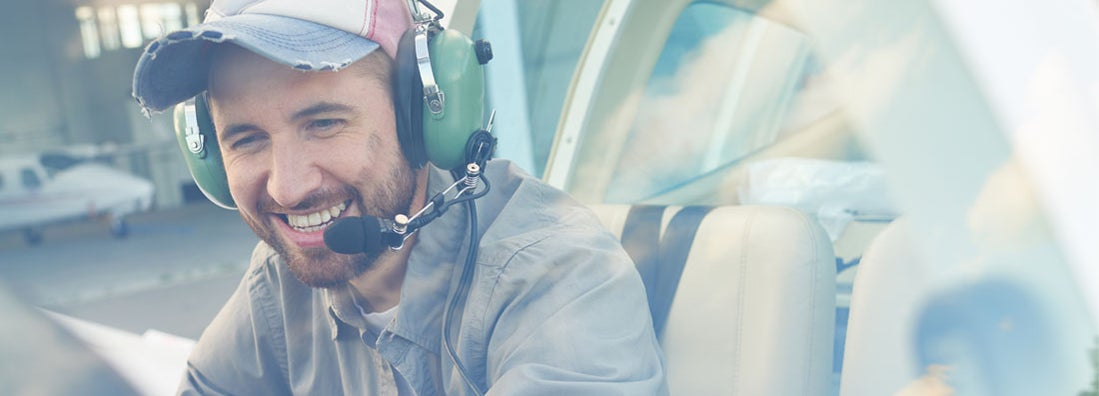 Young pilot sitting in cockpit and enjoying his job. Find Aviation Liability Insurance.