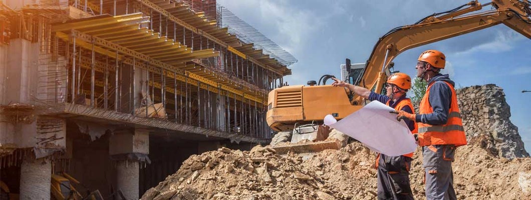 Engineers with blueprints at a construction site