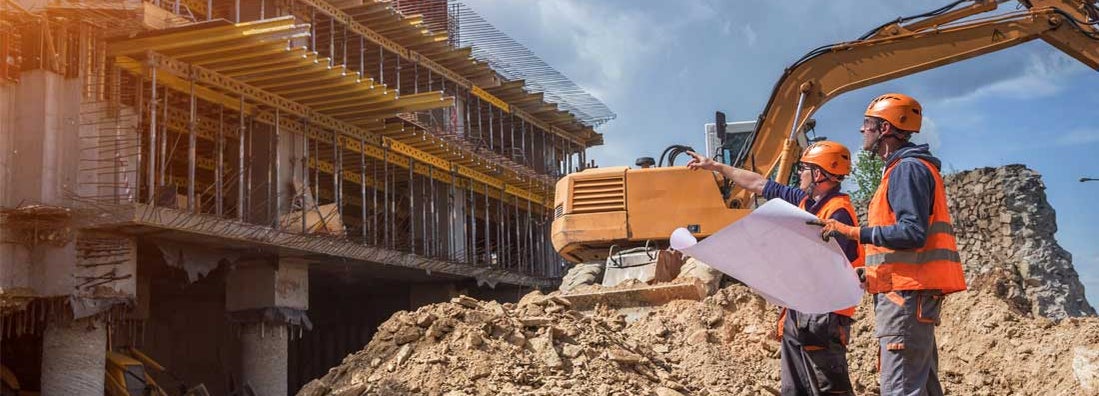 Engineers with blueprints at a construction site