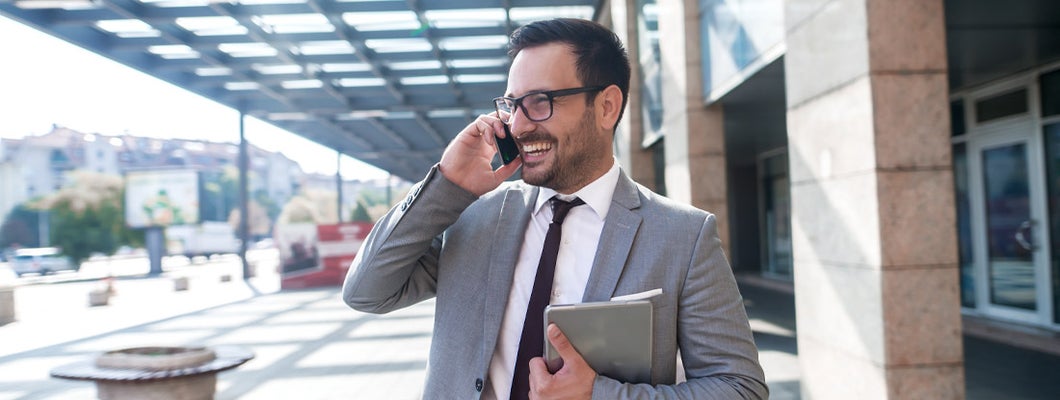 Modern businessman smiling and talking on the phone. Find commercial property insurance.