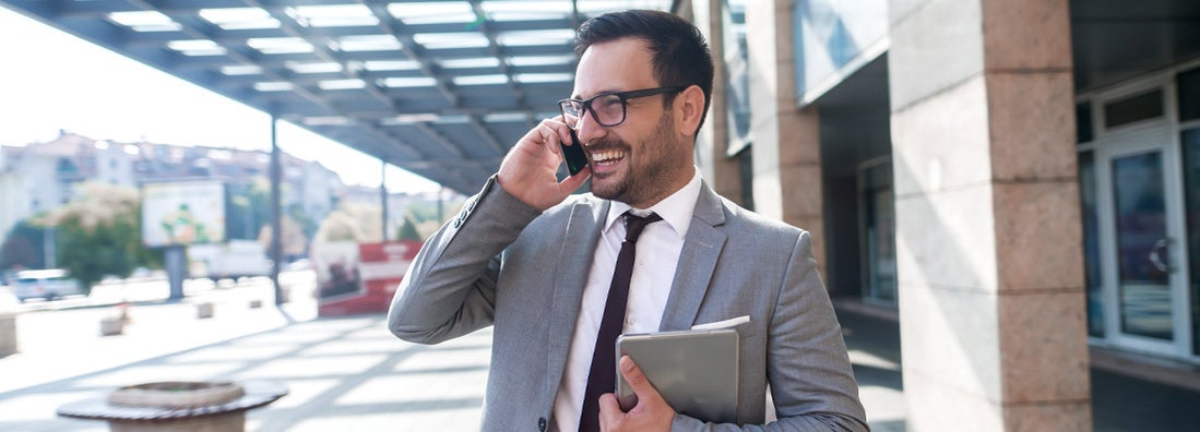 Modern businessman smiling and talking on the phone. Find commercial property insurance.