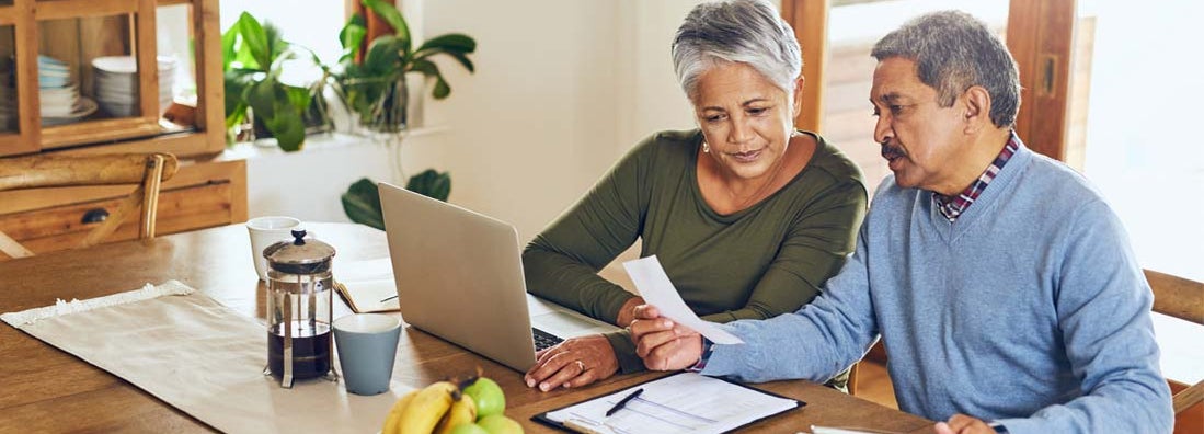 Senior couple using a laptop together at home. Long term care insurance benefits.