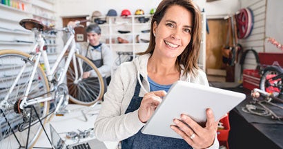 Female business owner looking at the online orders on a tablet. Find Small Business Coverage Types. 