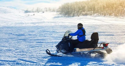 Man driving a snowmobile in Colorado. Snowmobile License Requirements & State Regulations.