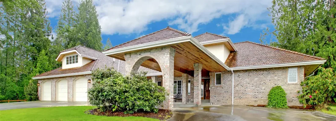 Beautiful curb appeal after rain. Large brick house with three garage spaces and driveway with arch. How to Find the Best Homeowners Insurance in Potomac, MD