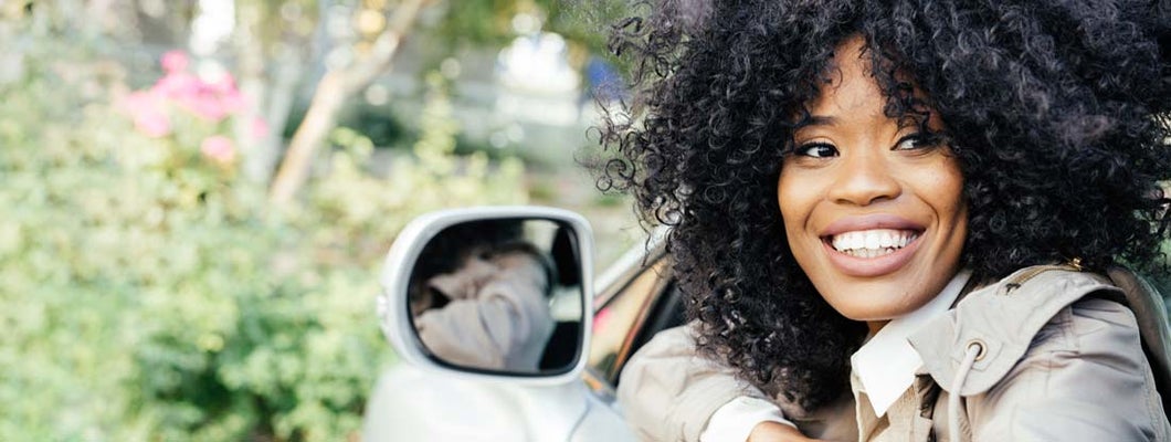 Smiling woman looking out of the car. Find Broad Form Auto Insurance.