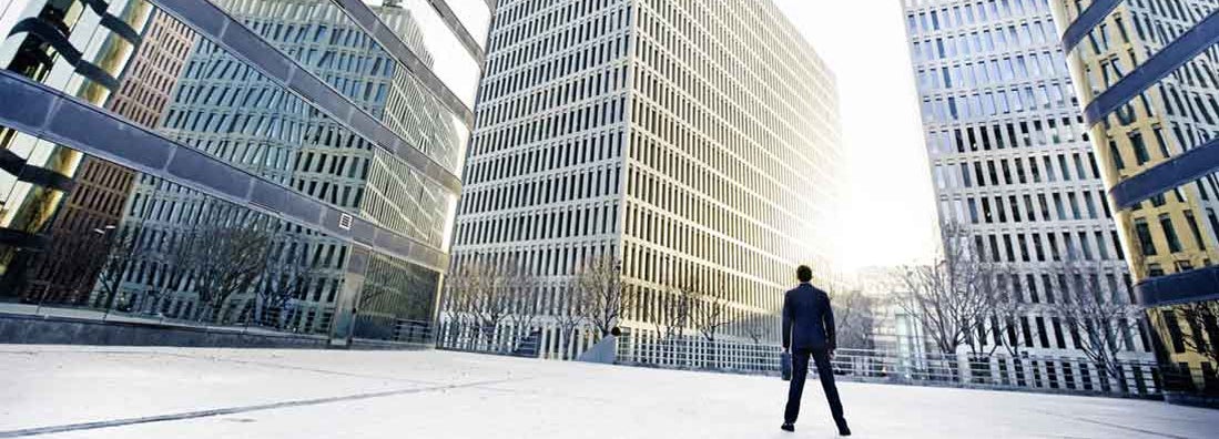 Businessman looking across the city financial district. Find premises liability insurance.