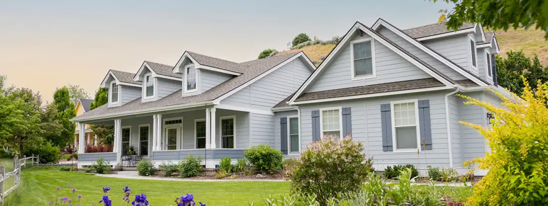 Suburban home at sunset with lawn and garden visible. 9 Steps to Buying the House of Your Dreams.