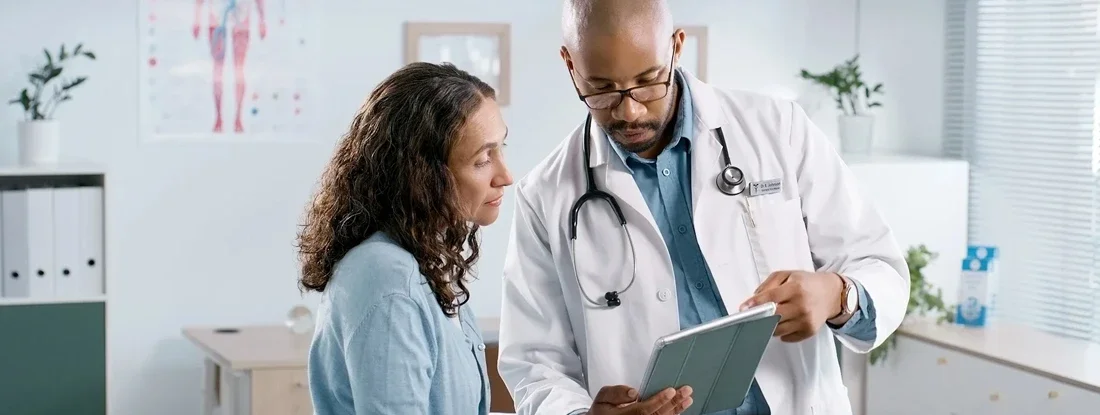 Doctor discussing medical results with woman at hospital. Major medical insurance.