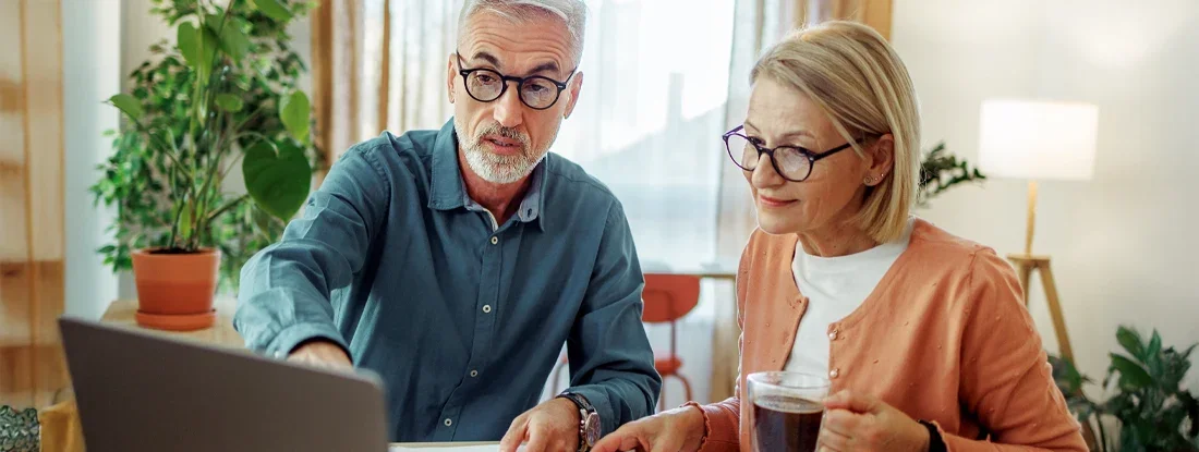 Couple going over bills at home. Find Health Insurance Discounts.