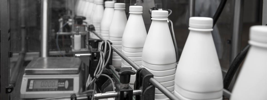 White plastic milk bottles on the conveyor in a dairy plant