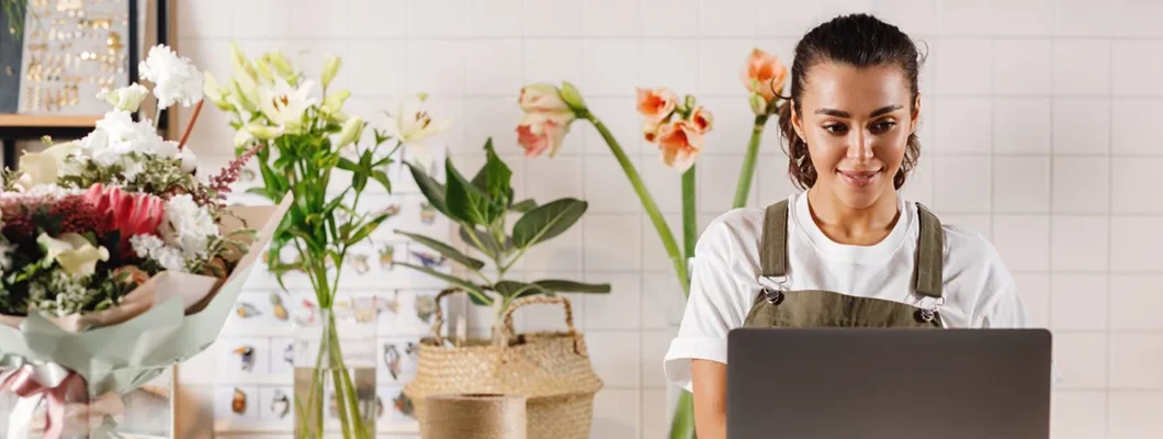 Small business owner working on her laptop in a flower shop. Find Auburn, Maine business insurance. 