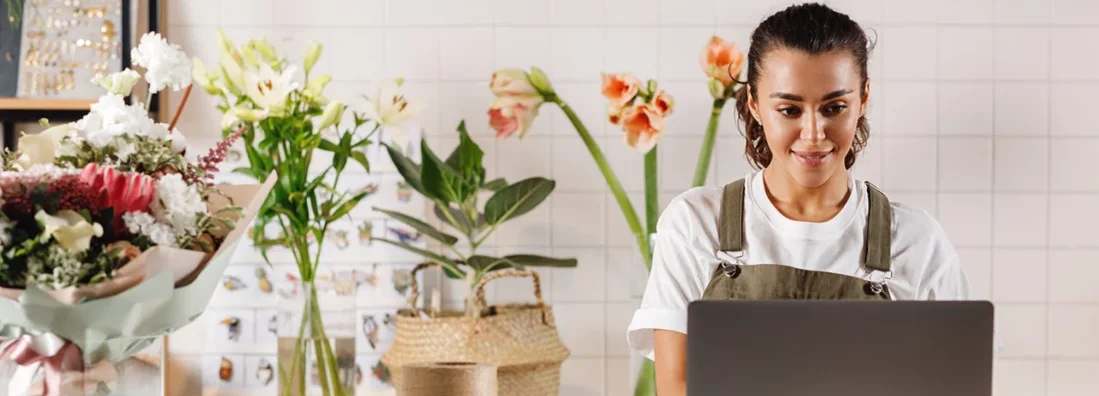 Small business owner working on her laptop in a flower shop. Find Auburn, Maine business insurance.