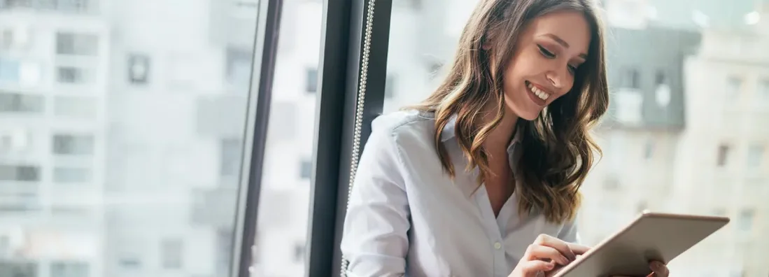 Businesswoman using a digital tablet while standing in front of windows. Find Narbet, Pennsylvania Business Insurance.