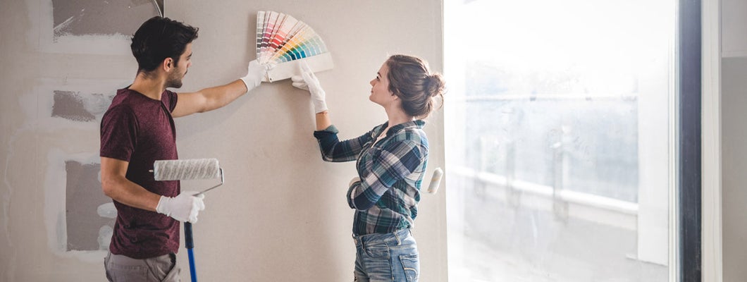 Young couple choosing the right color for their wall in new home. 6 diy home renovation projects that impact your insurance.