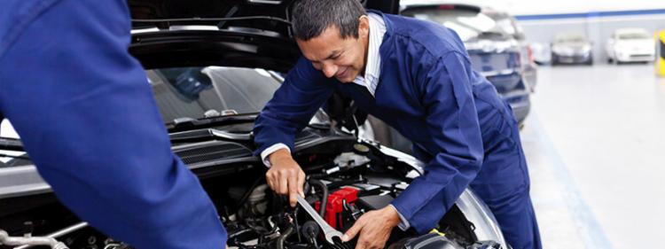 Two mechanics tuning up a car.