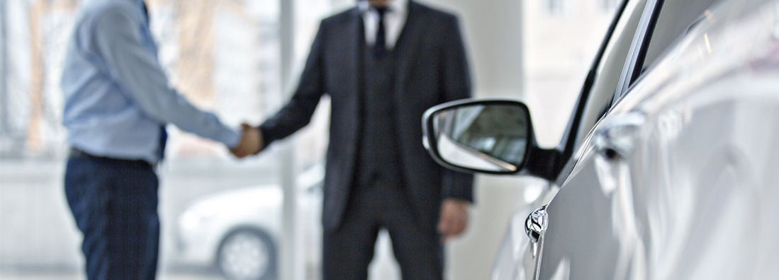 Handshake between two business people in a car showroom. Find Gap Insurance.