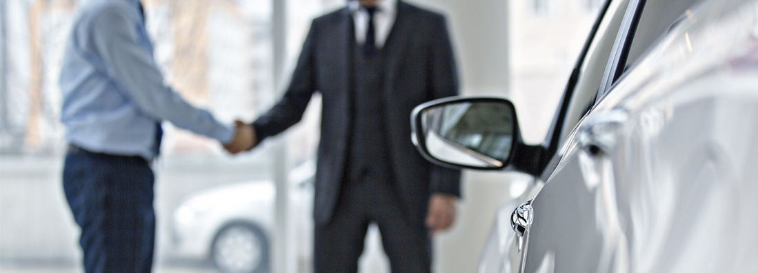Handshake between two business people in a car showroom. Find Gap Insurance. 