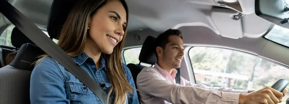 Couple driving a car wearing their seat belts and smiling. How to Find the Best Car Insurance Coverage in Los Alamos, New Mexico.