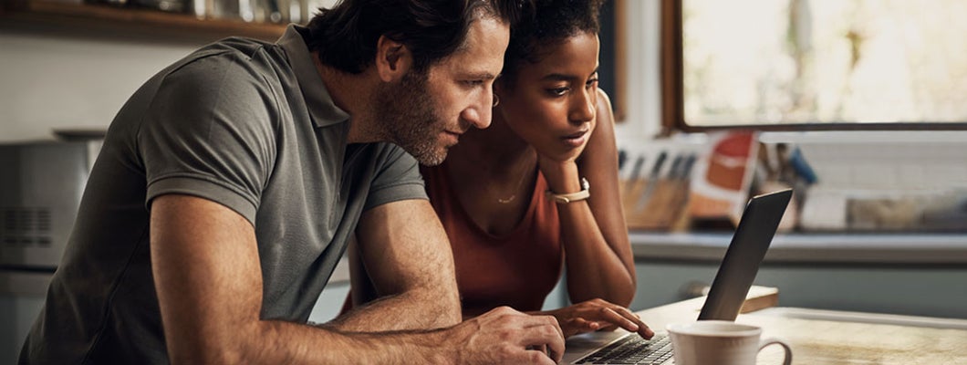 Couple using a laptop while doing their budget paperwork in their kitchen at home. 10 things to know about renewing insurance. 