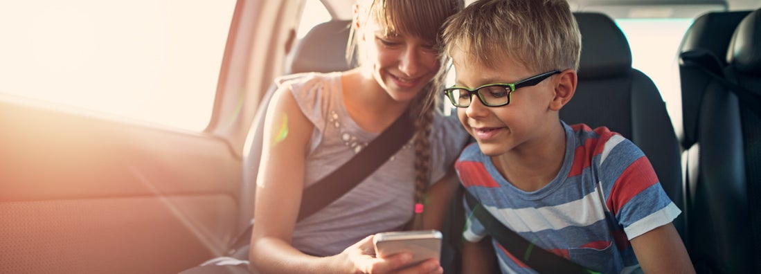 Kids playing smartphone during a road trip