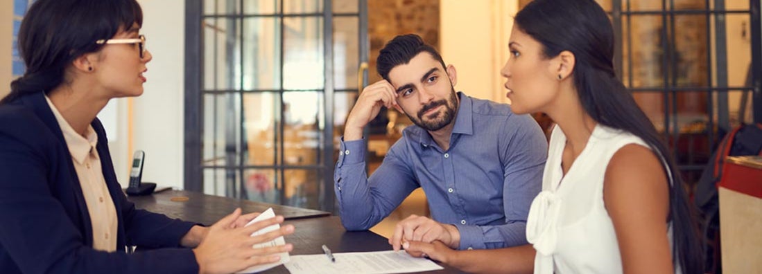 Couple meeting with a financial planner in an office. Find Trustee Insurance.