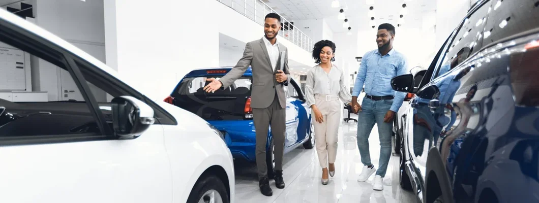Salesman Showing Luxury Car to Couple at Auto In Dealership. What Car Should I Buy?