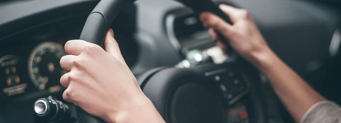 Hands on steering wheel while driving a car. How to Find the Best Car Insurance Coverage in The Woodlands, Texas.